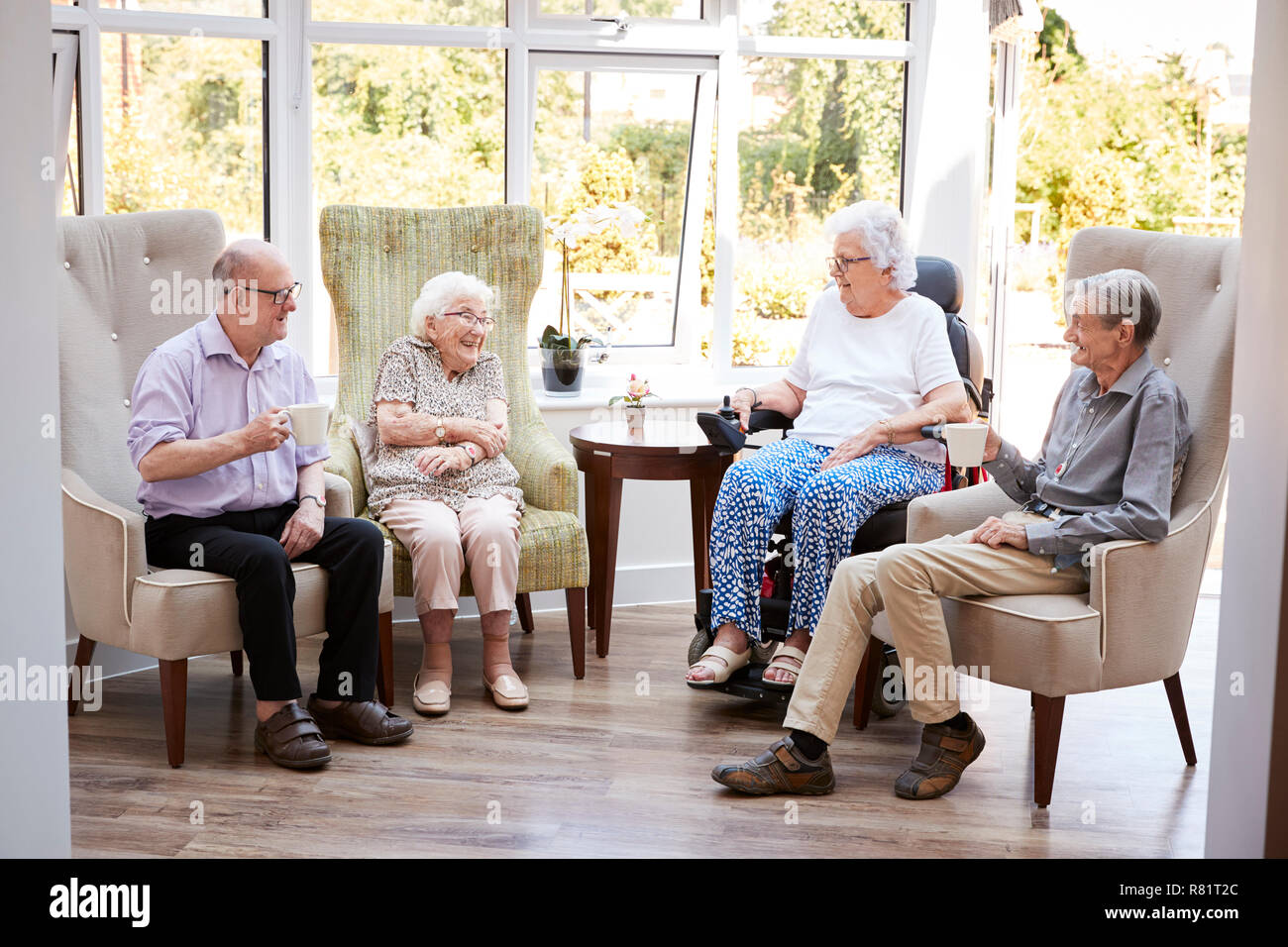 Männliche und weibliche Bewohner Sitzen in Stühlen und Gespräch in der Lounge des Seniorenheims Stockfoto