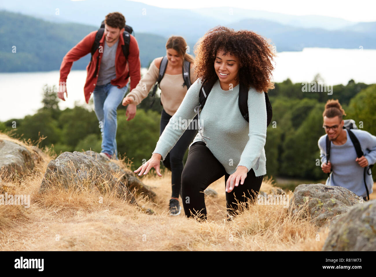 Eine multi-ethnische Gruppe für junge Erwachsene junge erwachsene Freunde lächelnd beim Klettern auf einem Berggipfel, in der Nähe Stockfoto