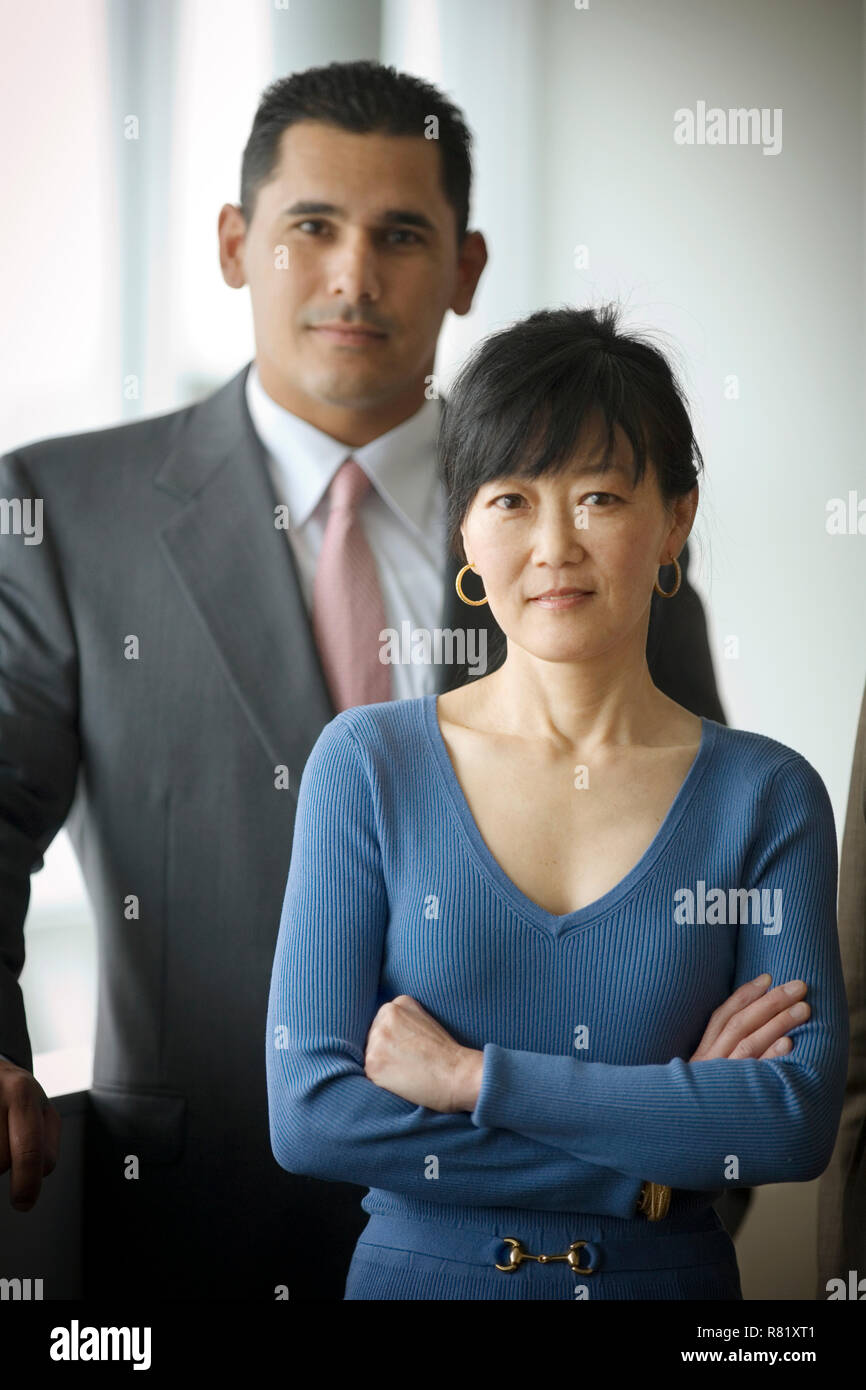 Porträt einer zuversichtlich, Mitte - erwachsene Frau, die vor ihrer männlichen Kollegen mit verschränkten Armen. Stockfoto