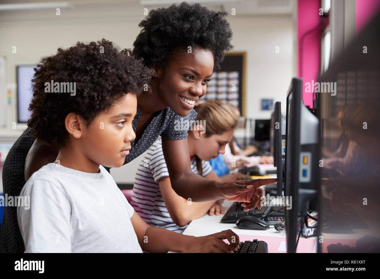 Lehrer helfen männliche Schüler der High School Kursteilnehmer an Bildschirmen arbeiten In Computer Klasse Stockfoto