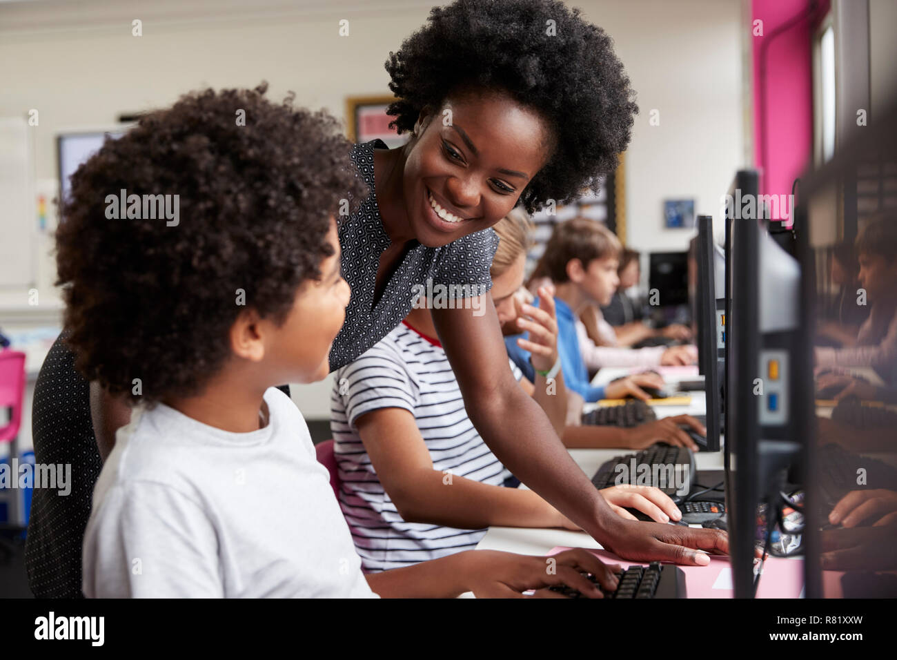 Lehrer helfen männliche Schüler der High School Kursteilnehmer an Bildschirmen arbeiten In Computer Klasse Stockfoto
