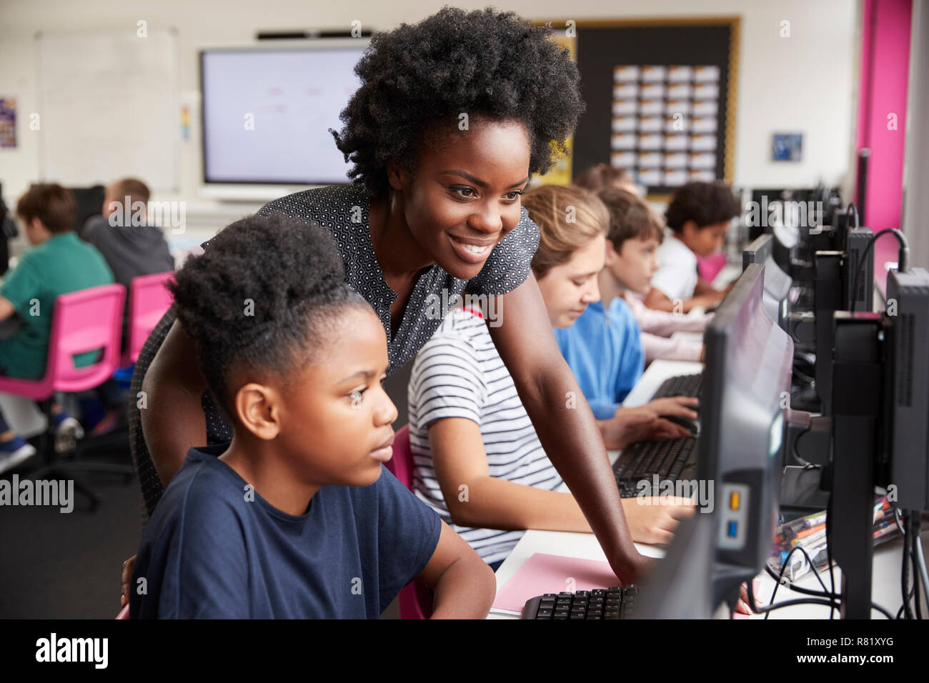 Lehrer helfen weiblichen Schüler der High School Kursteilnehmer an Bildschirmen arbeiten In Computer Klasse Stockfoto
