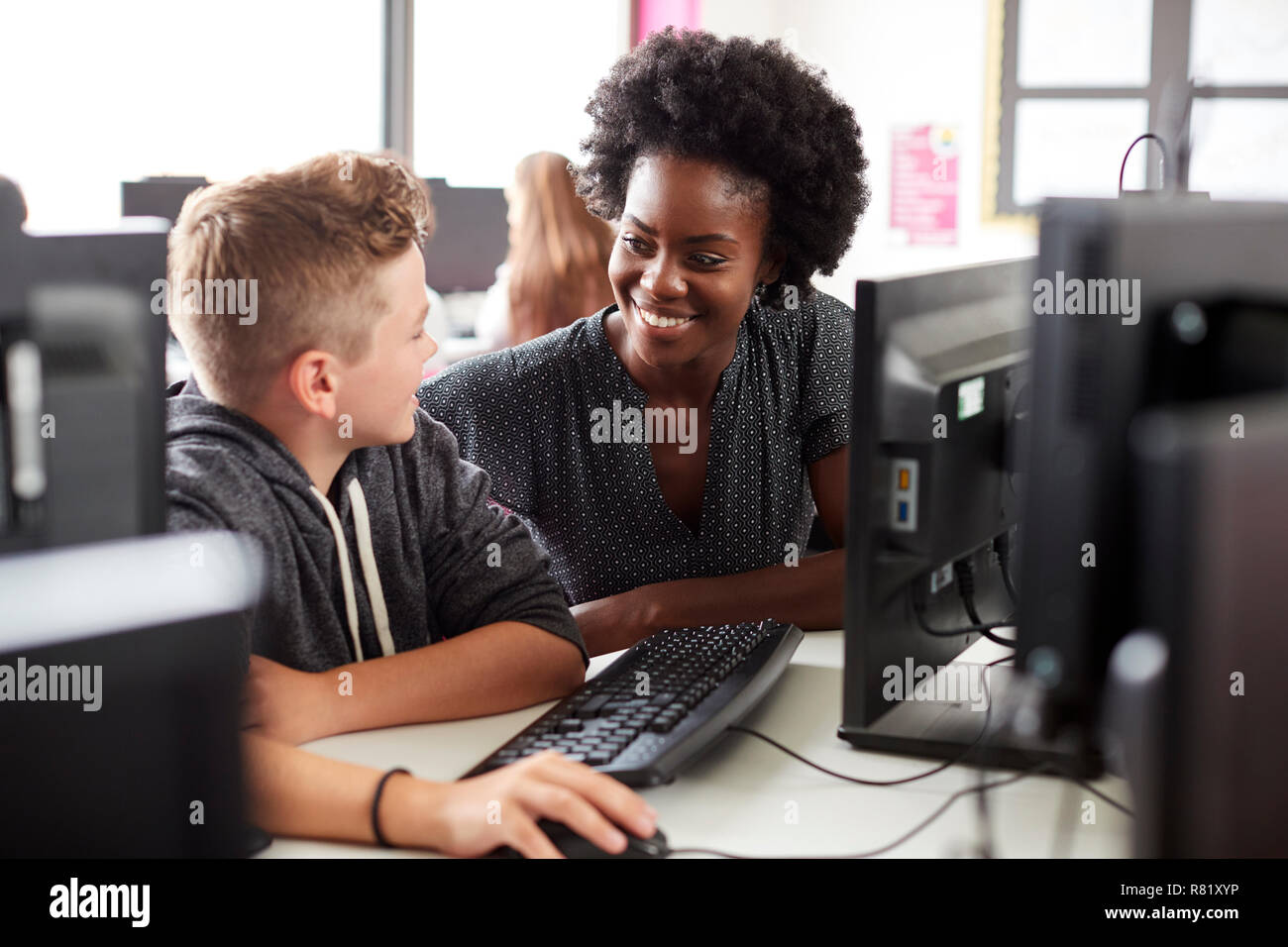 Lehrer helfen männliche Schüler Arbeiten am Bildschirm in Computer Klasse Stockfoto