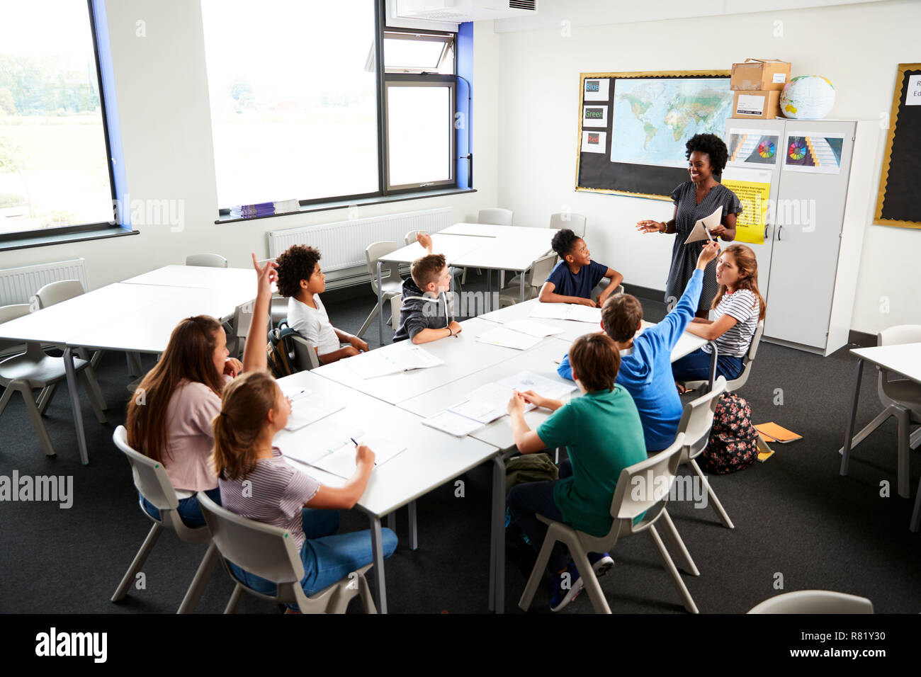 High School Schüler heben die Hände zu beantworten Frage durch den Lehrer im Klassenzimmer Stockfoto