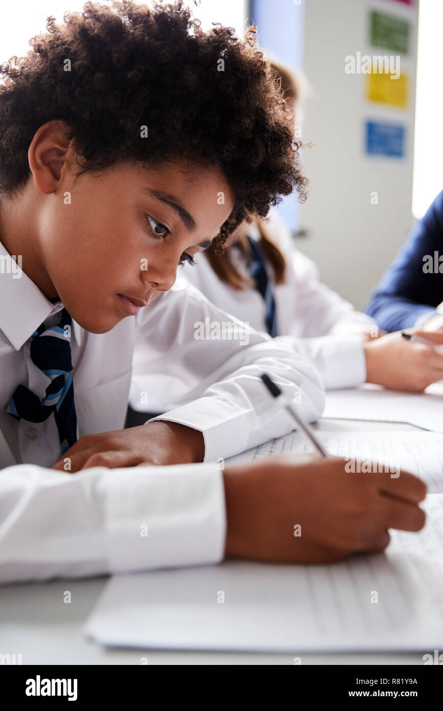 Männliche High School Student trägt Uniform Arbeiten am Schreibtisch Stockfoto