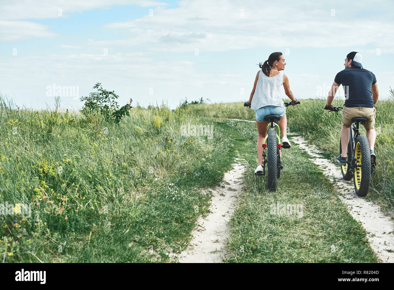 Junge Paare sind Radfahren auf dem Grünen Hügel. Ansicht von hinten Stockfoto