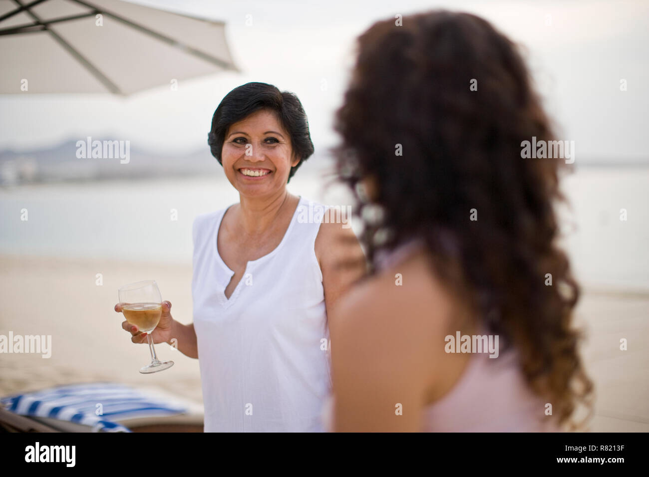 Frau und Tochter Wein trinken im Beach Resort Stockfoto