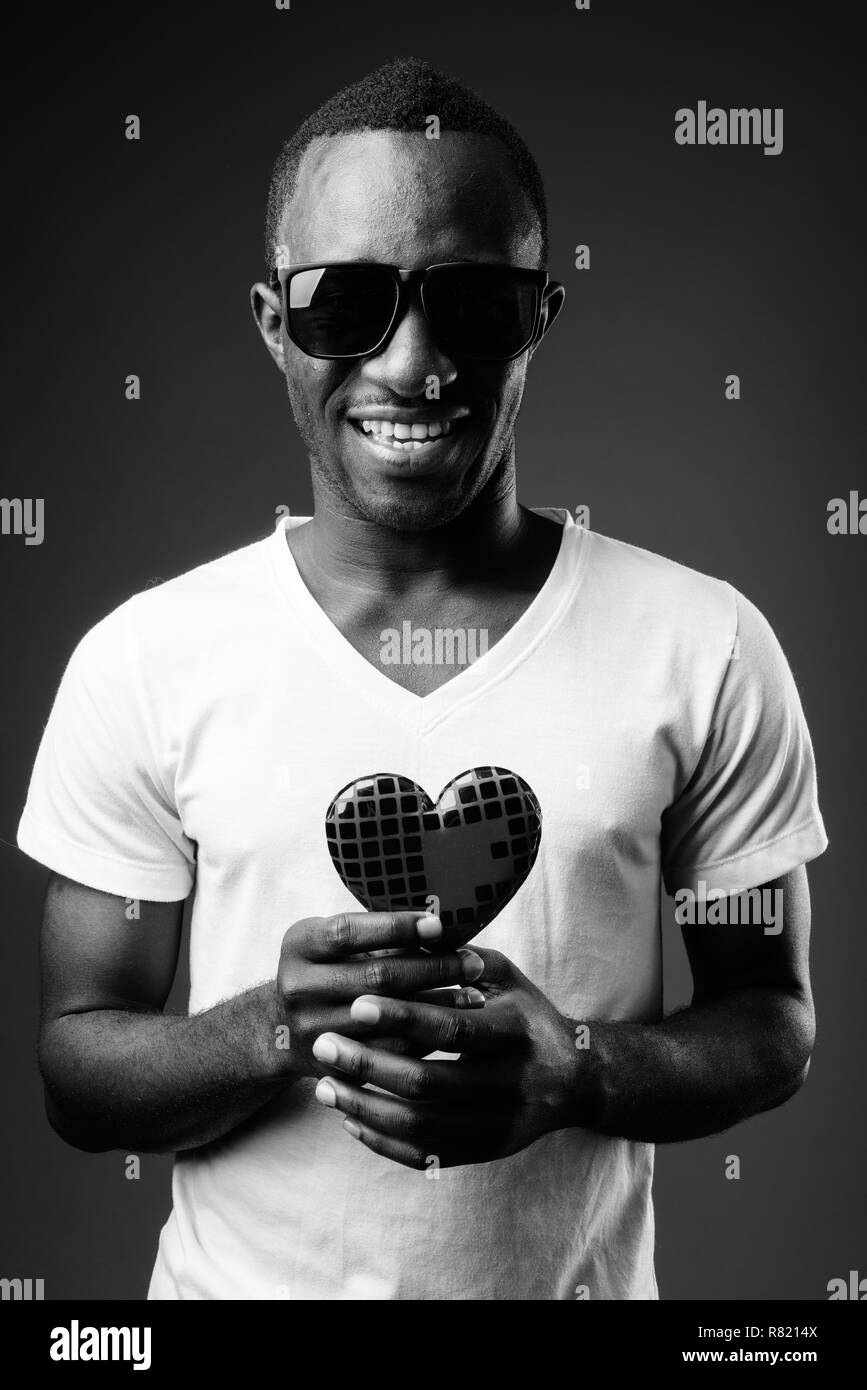 Junge glücklich afrikanischer Mann Sonnenbrille tragen und halten Herzen Stockfoto