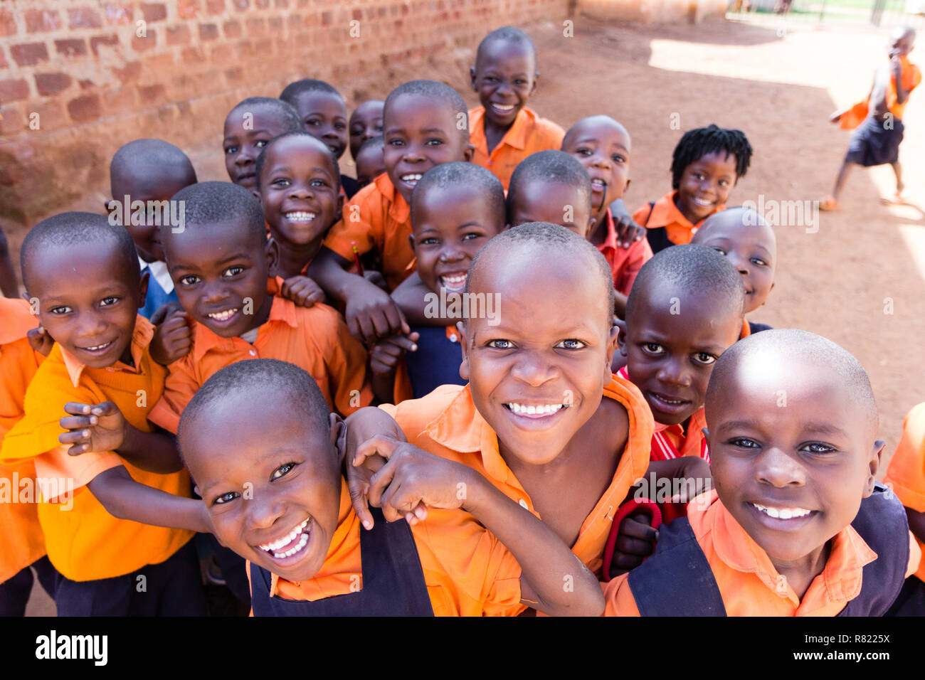 Eine Gruppe von Happy Grundschulkinder lächeln, lachen und winken. Sie sind in der Schule Uniformen gekleidet. Stockfoto