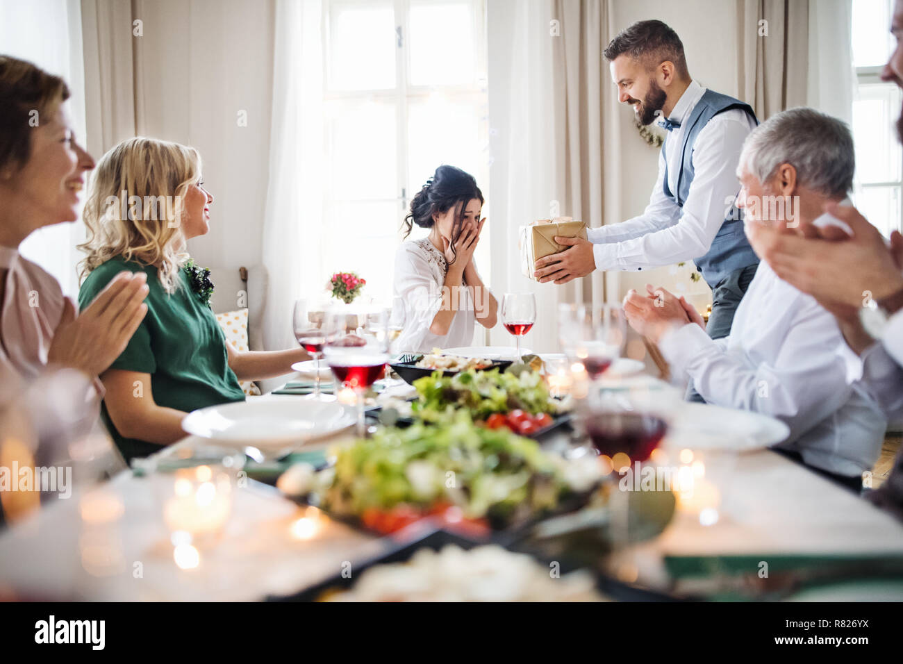 Ein Mann, der ein Geschenk überrascht junge Frau auf einer Geburtstagsfeier in der Familie. Stockfoto