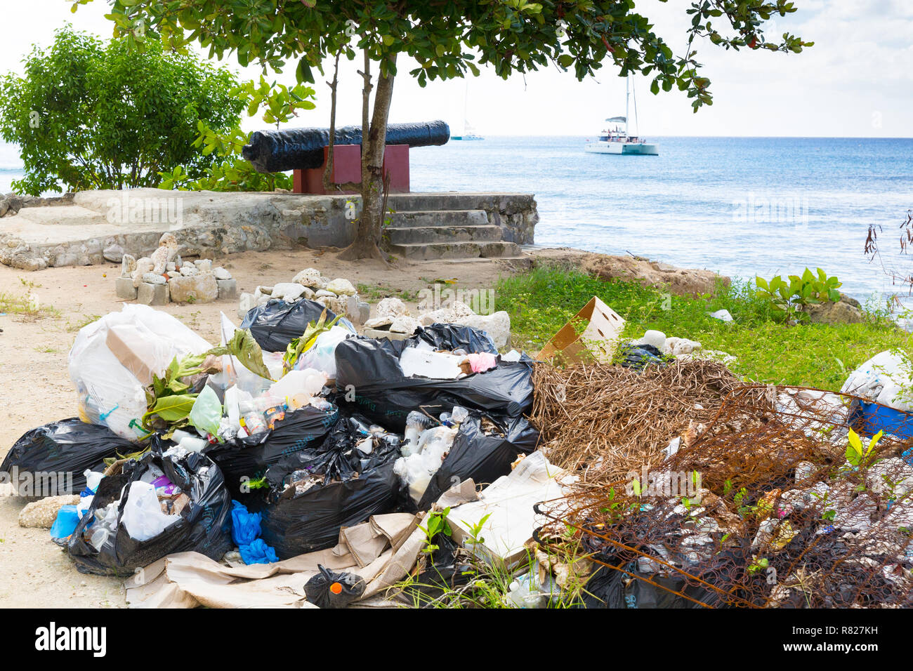 Plastik und andere Abfälle entsorgt auf einem Shoreline in die Karibik, während Urlauber auf einer Luxusyacht nur off-shore-Revel Stockfoto