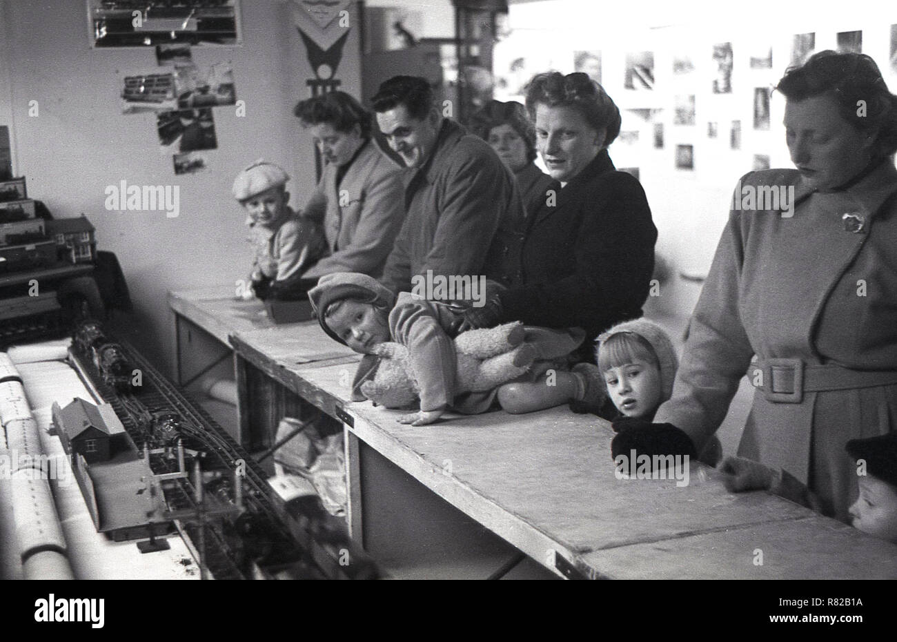 1950, historische, mit ihren Eltern, junge Kinder schiefen über den Zähler einen besseren Blick auf den Zug zu erhalten, stellen Sie eine Ausstellung für Modelleisenbahnen. Stockfoto