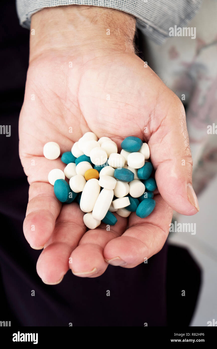 Nahaufnahme eines Senior kaukasischen Mann mit einem Stapel von verschiedenen Pillen in seiner Hand. Stockfoto