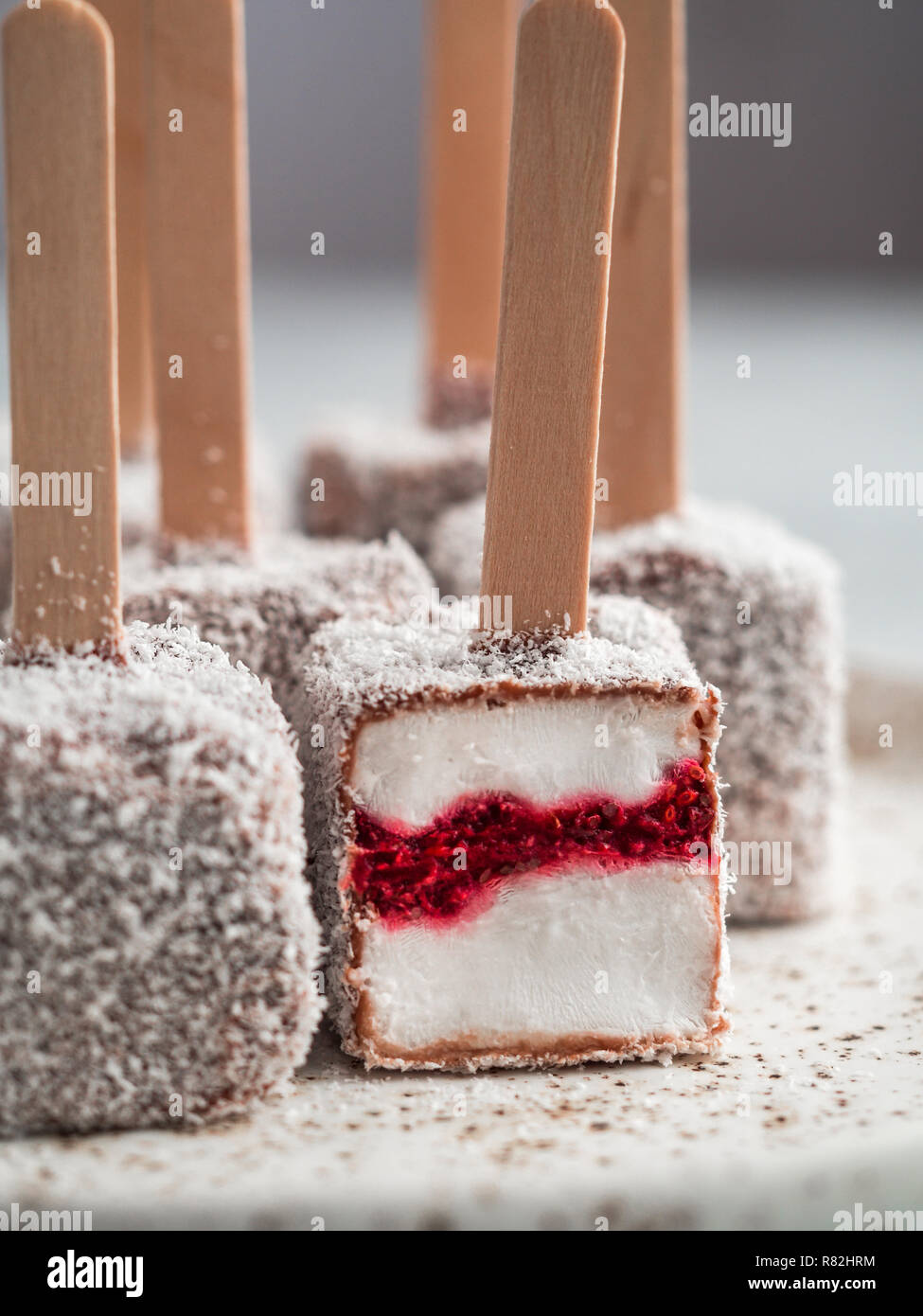 Hausgemachte raw lamington Eis springt auf hellen Hintergrund. Australische süße Nachspeise lamington mit Chia und Himbeeren Marmelade, Schokolade und Kakao. Veganes essen Rezept und Idee. Kopieren Sie Platz. Nahaufnahme Stockfoto