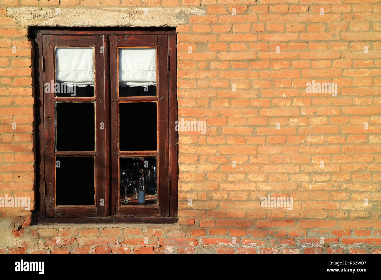Dunkel Braun Holz- Fenster auf Terrakotta gemauerte Wand im Sonnenlicht Stockfoto