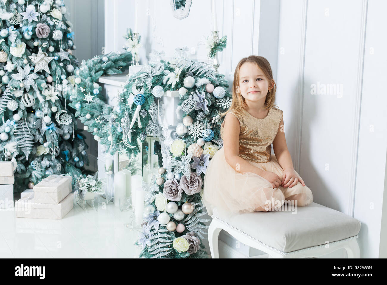Süße Mädchen in schönen Kleid sitzen am Kamin und Weihnachtsbaum. Stockfoto