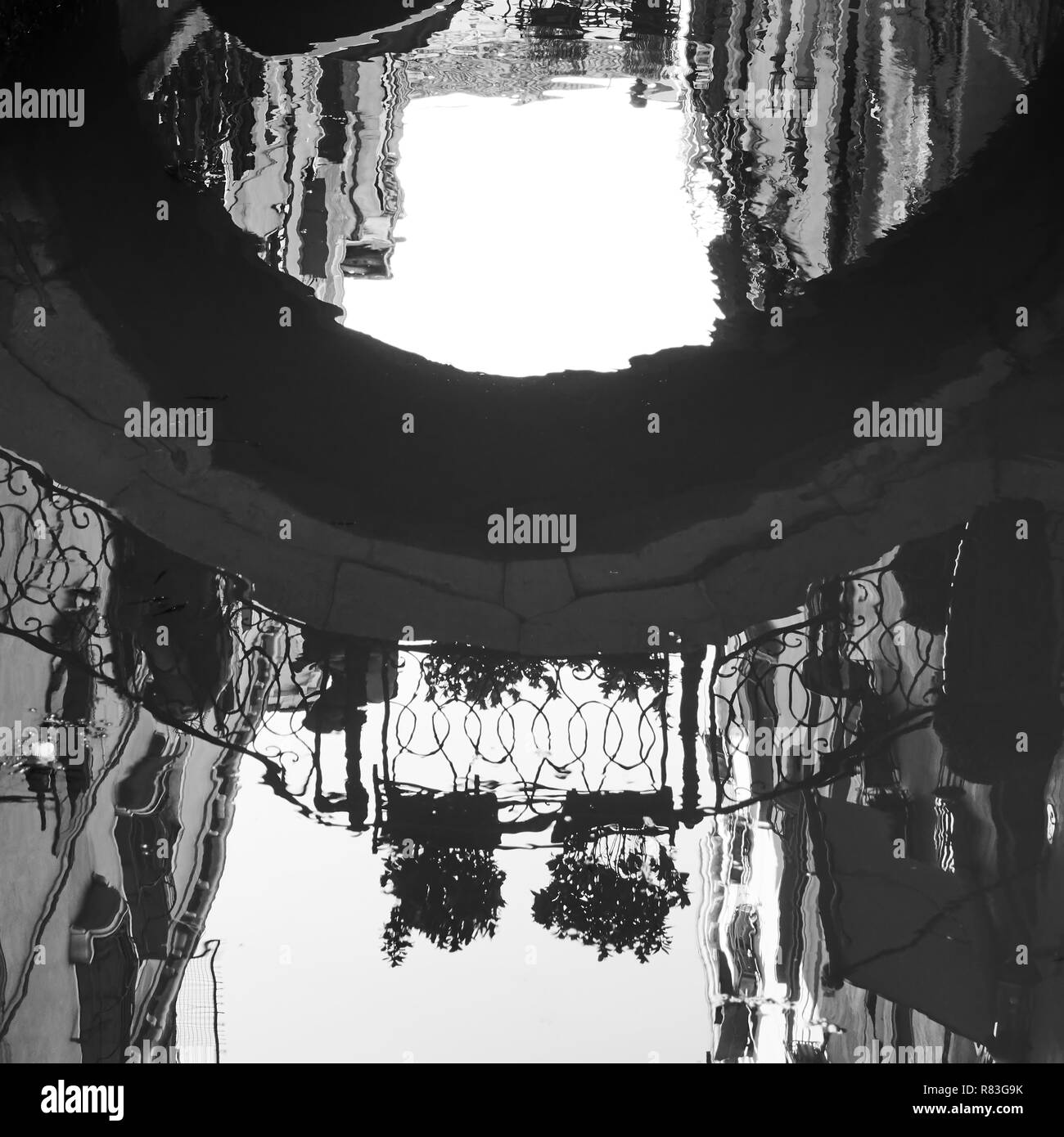 Venezianischer Spiegel - Häuser und kleine Brücke reflektieren im Wasser der Canal, Venice, Italien. Schwarz/Weiß-Bild Stockfoto