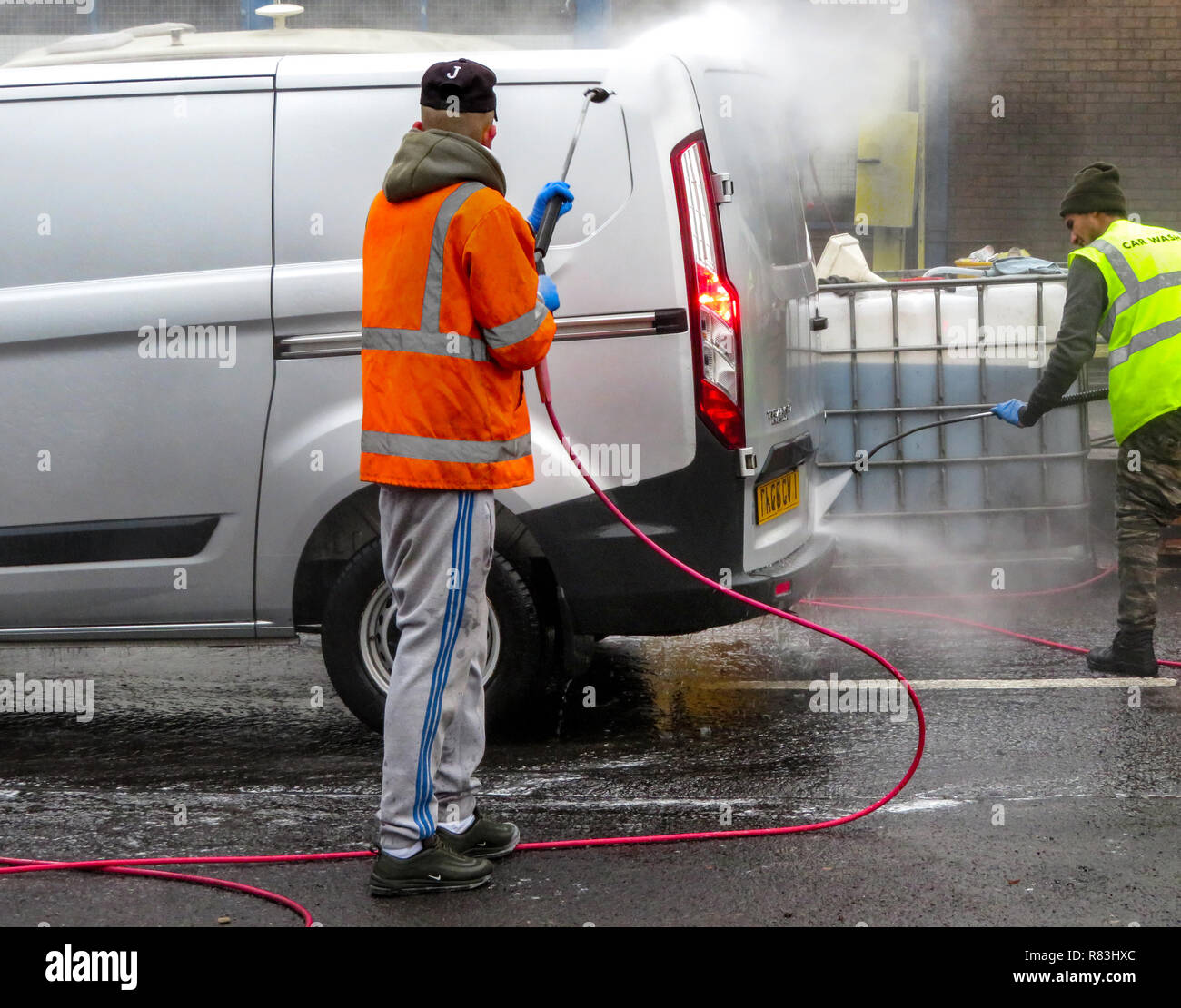 2 Männer mit Wasserstrahl Spray's Hand ein Fahrzeug in Rotherham, South Yorkshire, England waschen Stockfoto