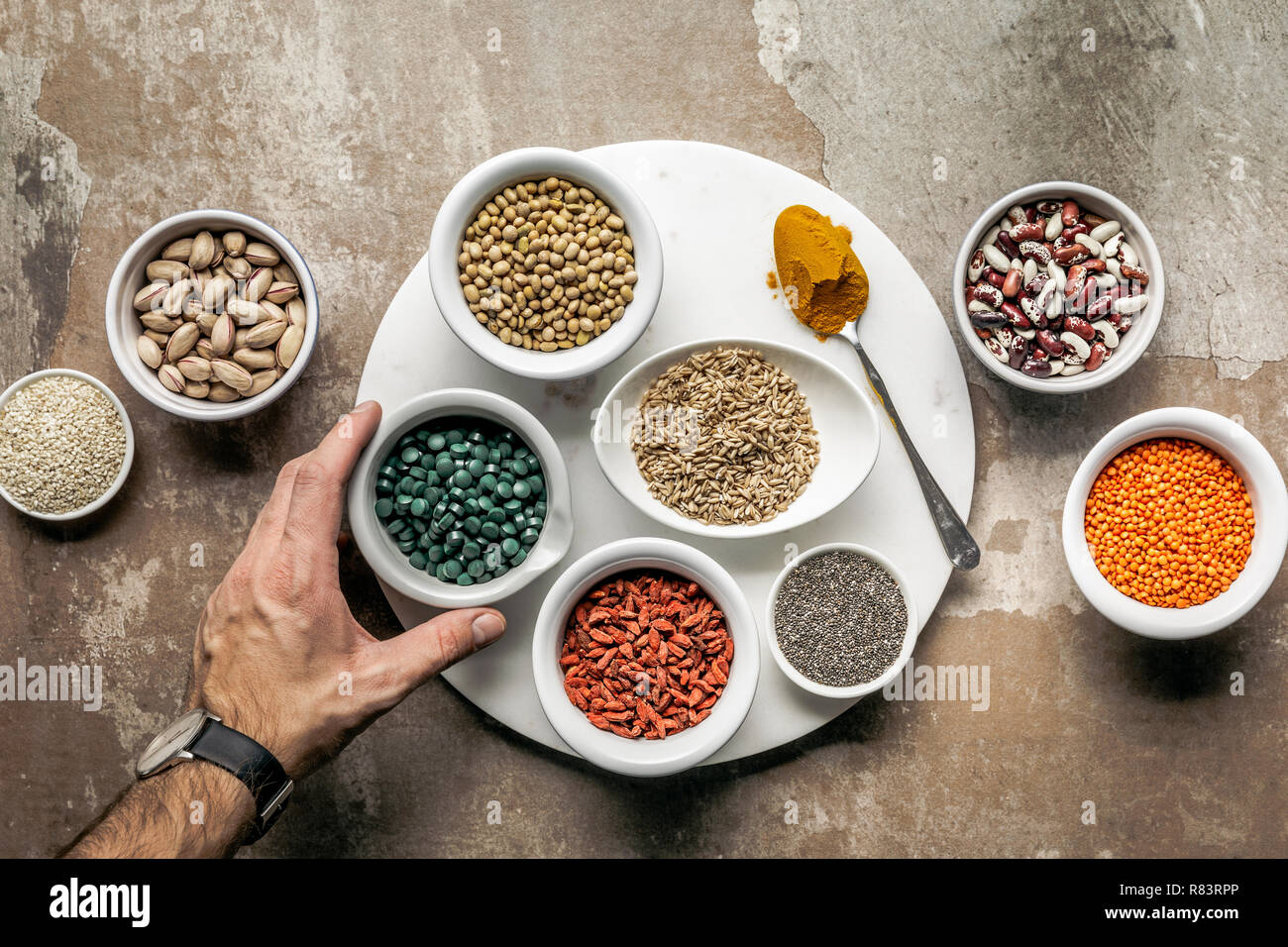 7/8-Ansicht von Mann mit Spirulina mit Superfoods und Leguminosen auf strukturierte rustikalen Hintergrund Stockfoto