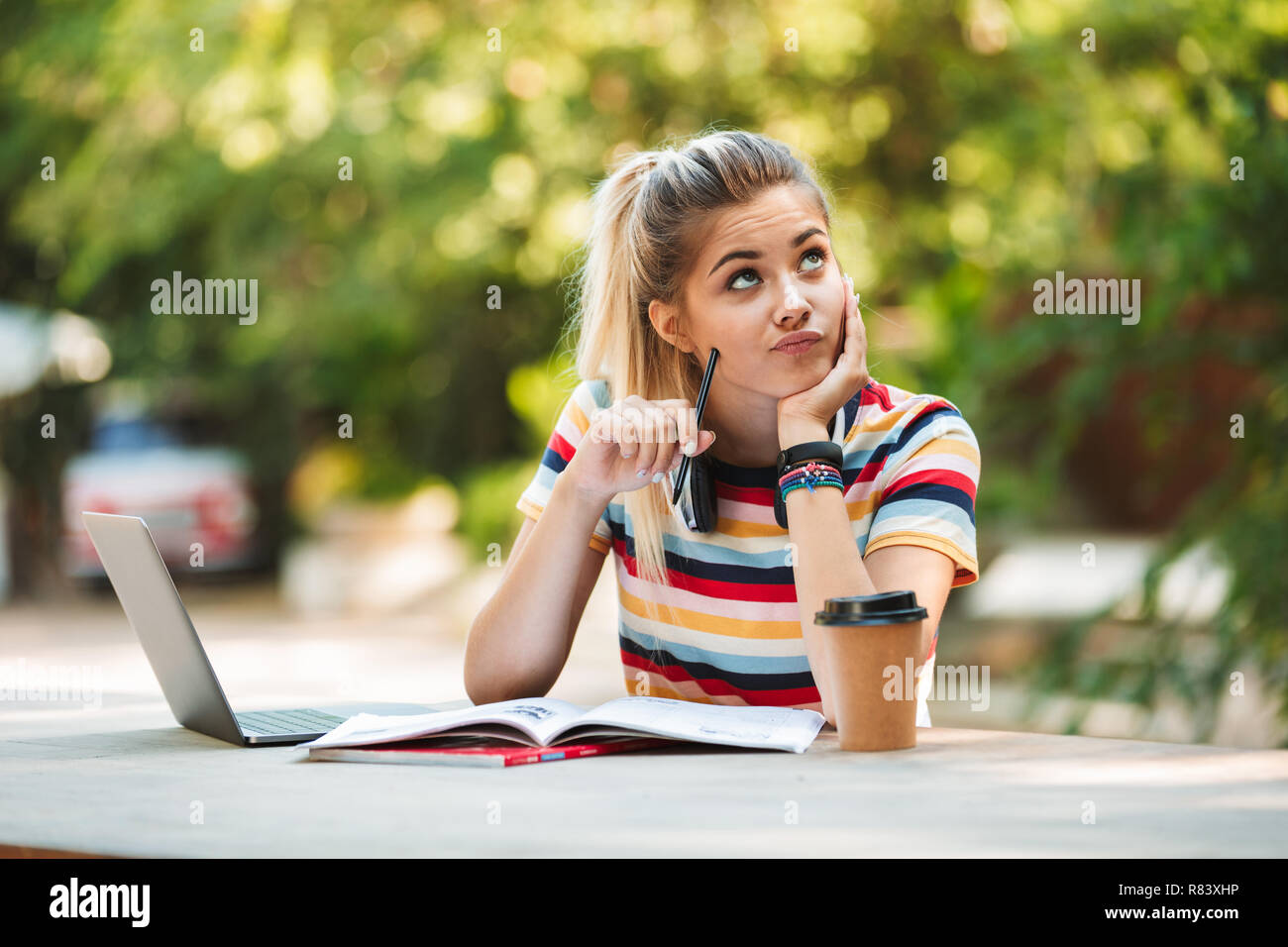 Bild eines Denkens nachdenkliche junge süße Mädchen student sitzt im Park mit Laptop Computer schreiben. Stockfoto