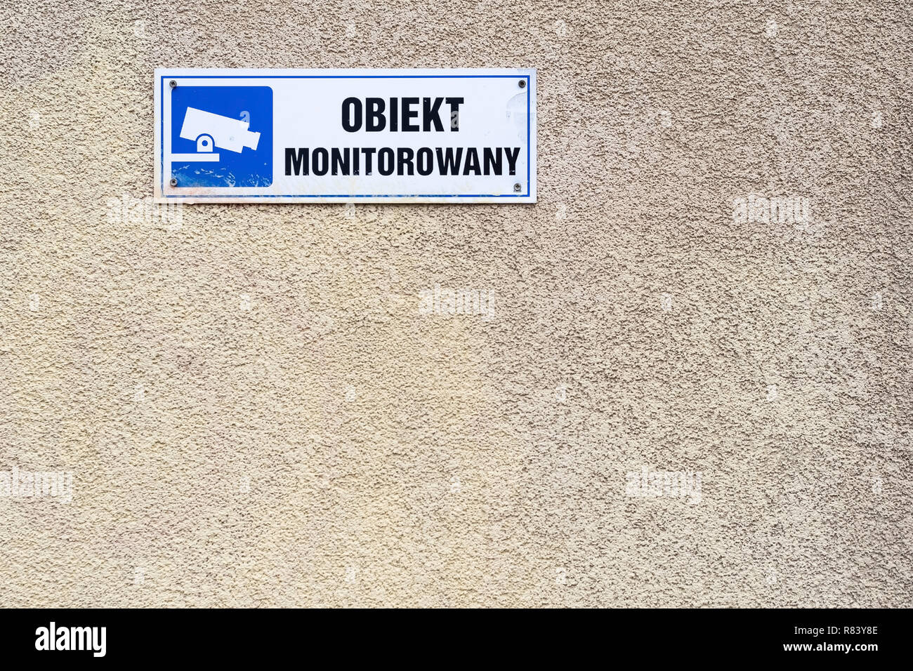 Unter Videoüberwachung Text in Polnisch, blau CCTV-Symbol an der Wand in Warschau, Polen Stockfoto