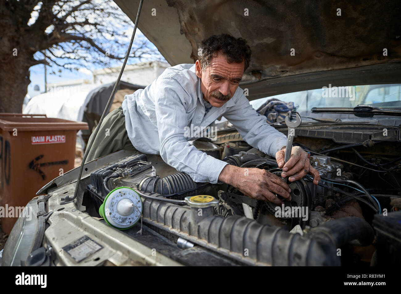 Ein yeziden Mann arbeitet am Motor ist mit seinem Auto in ein Lager für Binnenvertriebene in Dawodiya in der Irakischen Region Kurdistan. Stockfoto