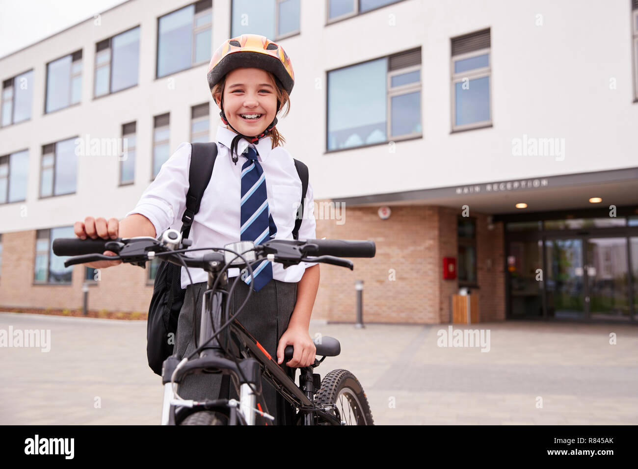 Portrait von weiblichen High School Student trägt Uniform mit Fahrrad ausserhalb der Schule Gebäude Stockfoto