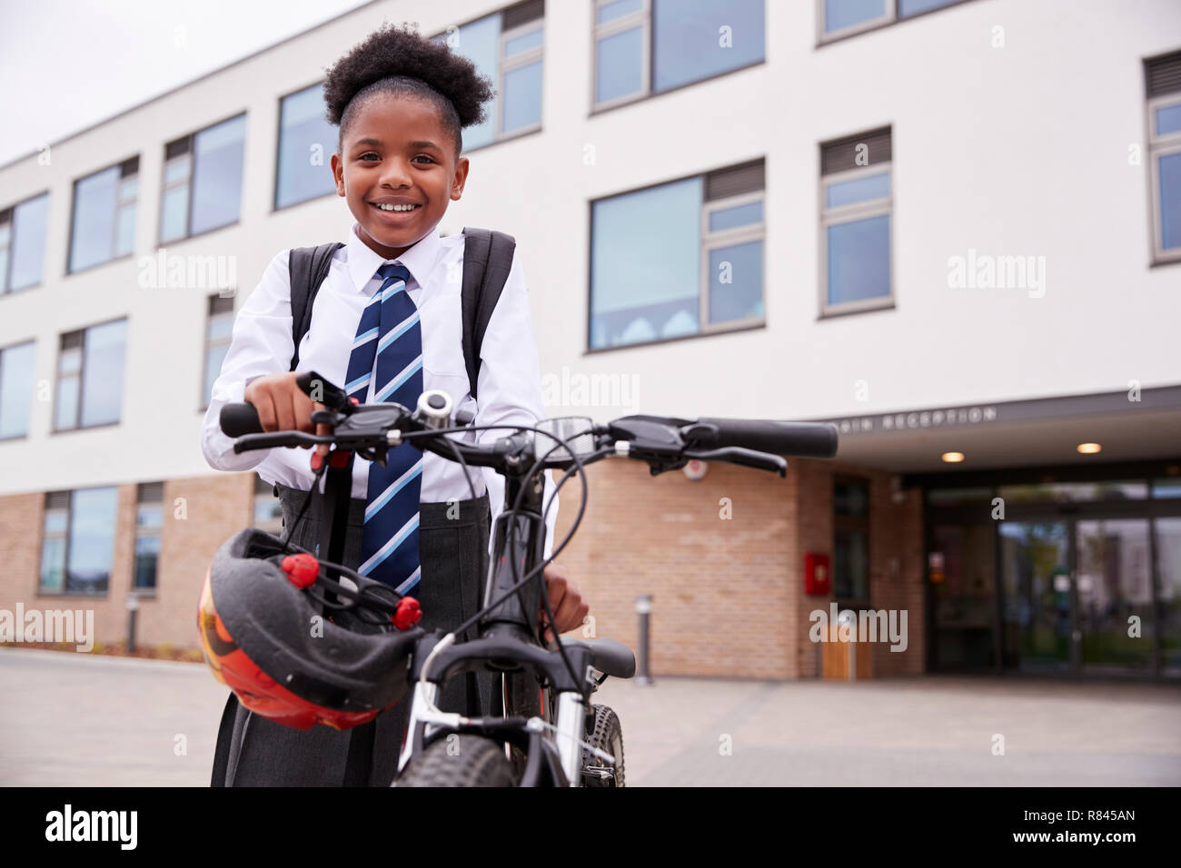 Portrait von weiblichen High School Student trägt Uniform mit Fahrrad ausserhalb der Schule Gebäude Stockfoto