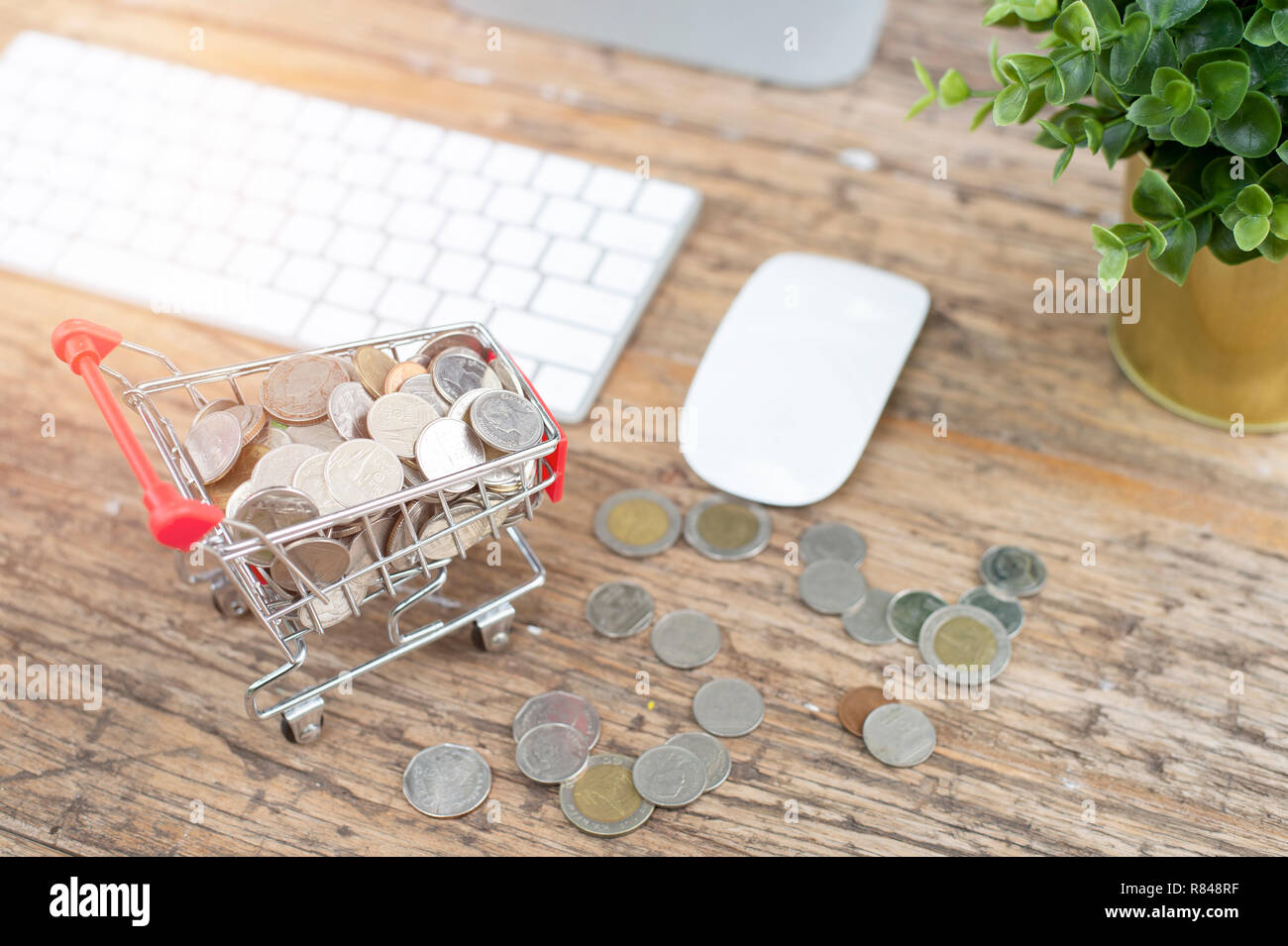 Geld und Münzen Warenkorb Trolley auf Tisch Holz Hintergrund für Ausgaben, Investitionen, Business und Finanzen Konzept zu mini Stockfoto