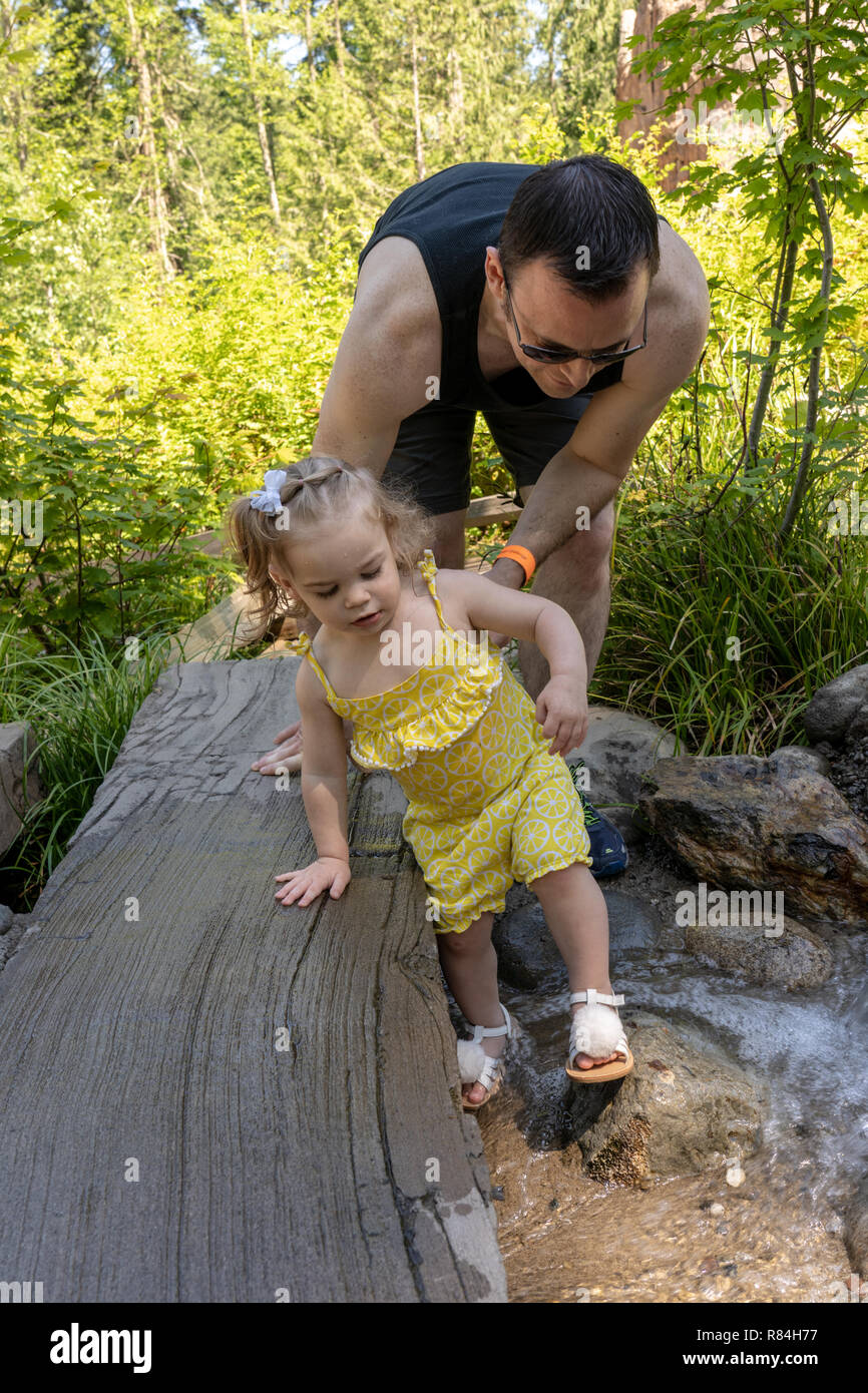 Eatonville, Washington, USA. Vater helfen, seine 18 Monate alte Mädchen im seichten Wasser waten. (MR) Stockfoto