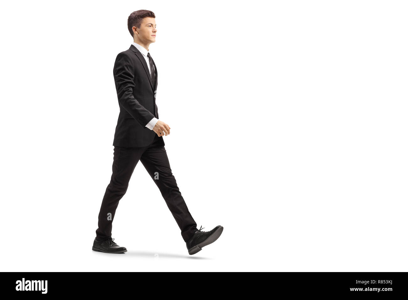 Volle Länge Schoß eines jungen gutaussehenden Mann in einem schwarzen Anzug zu Fuß auf weißem Hintergrund Stockfoto