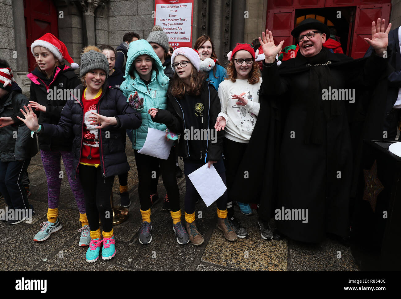 Mitarbeiter von St. Ann's Fred Deane (rechts) mit Mitgliedern des Chors of Kildare Place National School bei der Eröffnung des Black Santa 2018 sitzen in St. Ann's Church, Dawson Street, Dublin. Stockfoto
