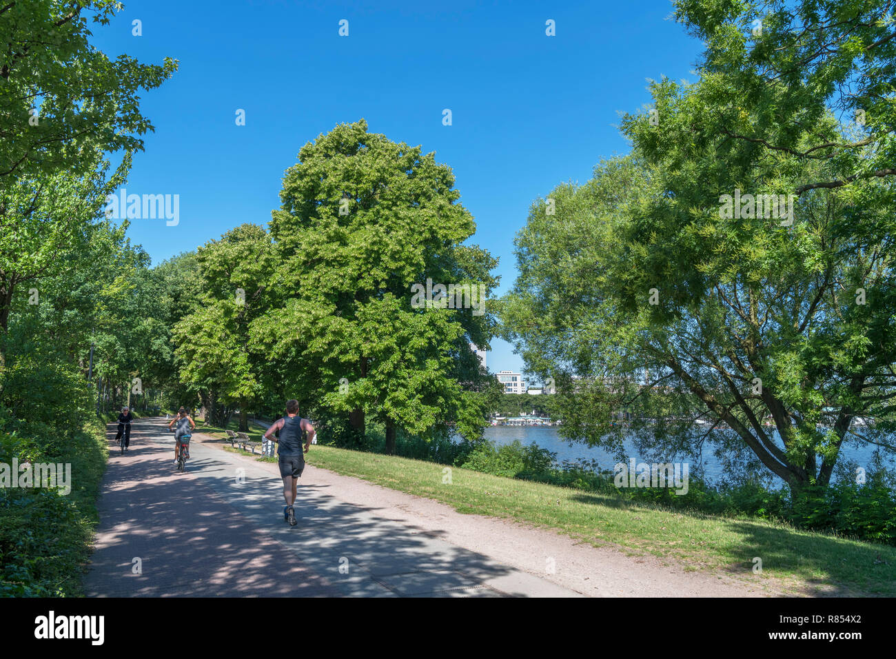 Läufer und Radfahrer auf dem Weg entlang der Außenalster (Außenalster), ein künstlicher See in Hamburg, Deutschland Stockfoto