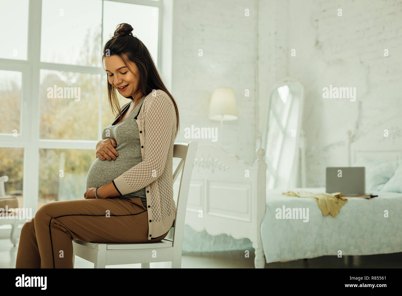 Vorbereitung für die Mutter. Eine schwangere Frau sitzt in ihrem Schlafzimmer Stockfoto