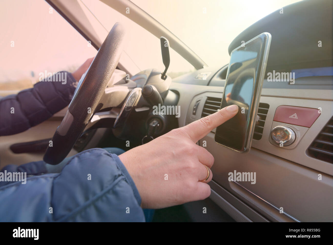 Frau mit smart phone als Navigation während der Fahrt das Auto. Riskantes Fahrverhalten Konzept Stockfoto