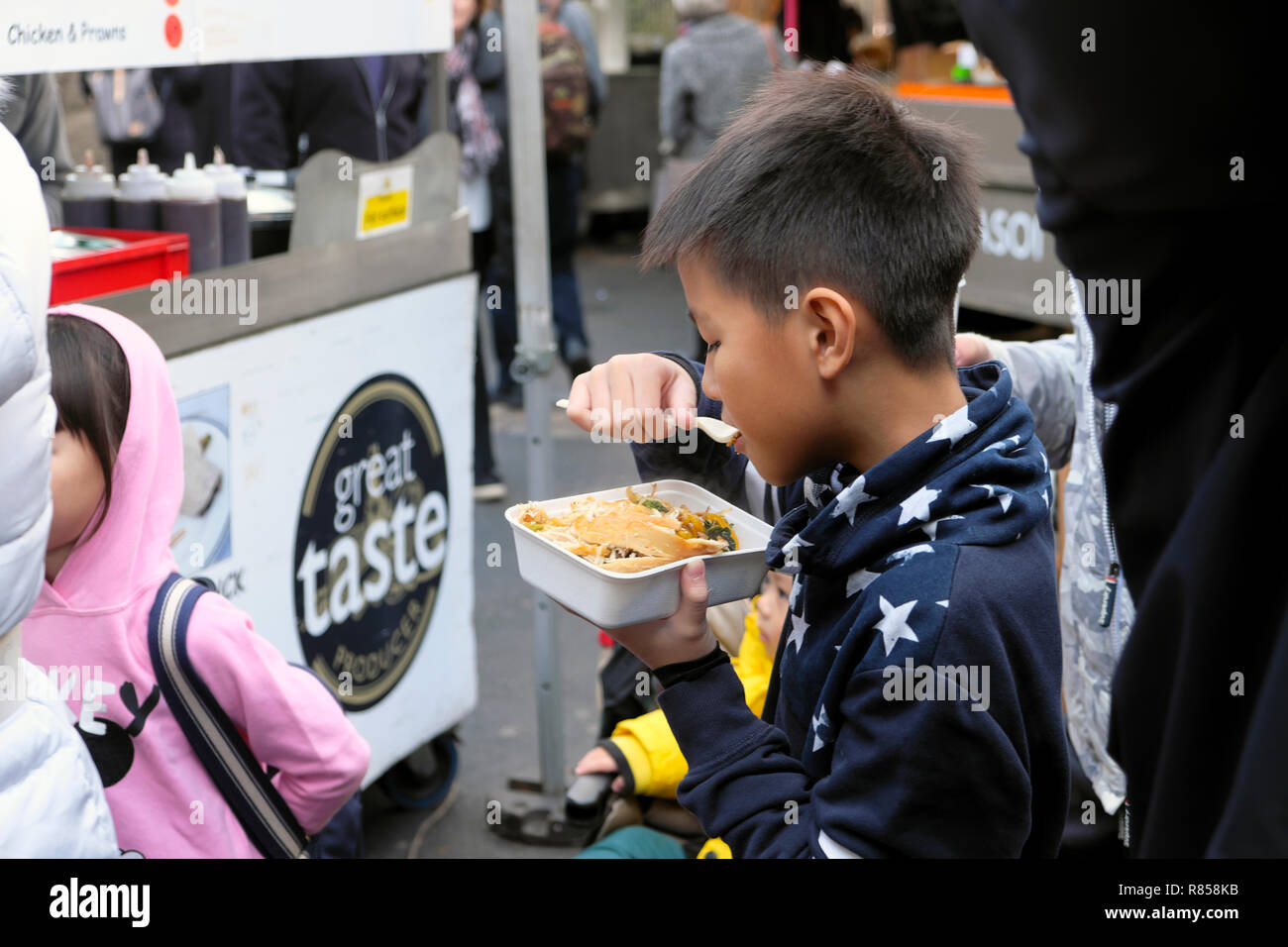 Ein junger chinesischer Junge essen Essen vom Borough Market Stall in London England UK KATHY DEWITT Stockfoto
