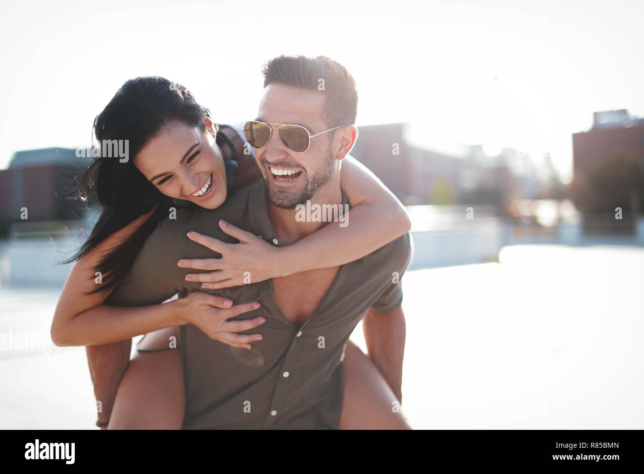 Glückliche junge Kaukasier urban Paar lachen und tun Huckepack auf draußen, Glück Stockfoto