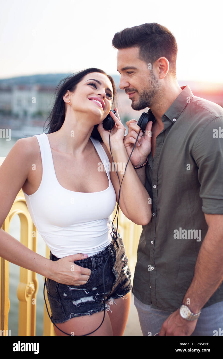 Glückliche junge trendige kaukasischen Paar teilen Kopfhörer bei im Freien, Hören von Musik Stockfoto