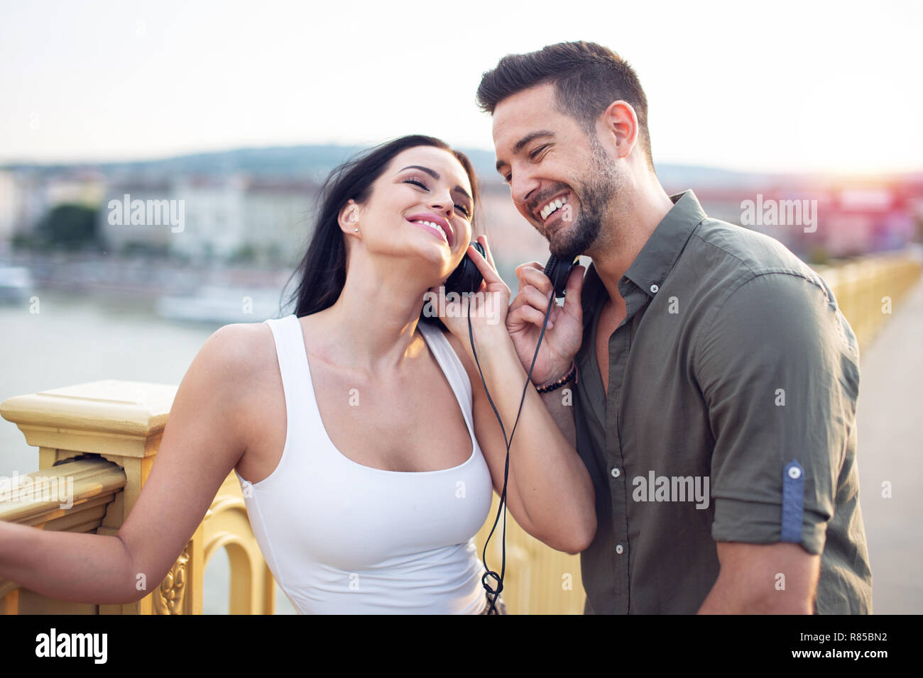 Glückliche junge urbane Paar teilen Musik von Kopfhörern bei im Freien Stockfoto