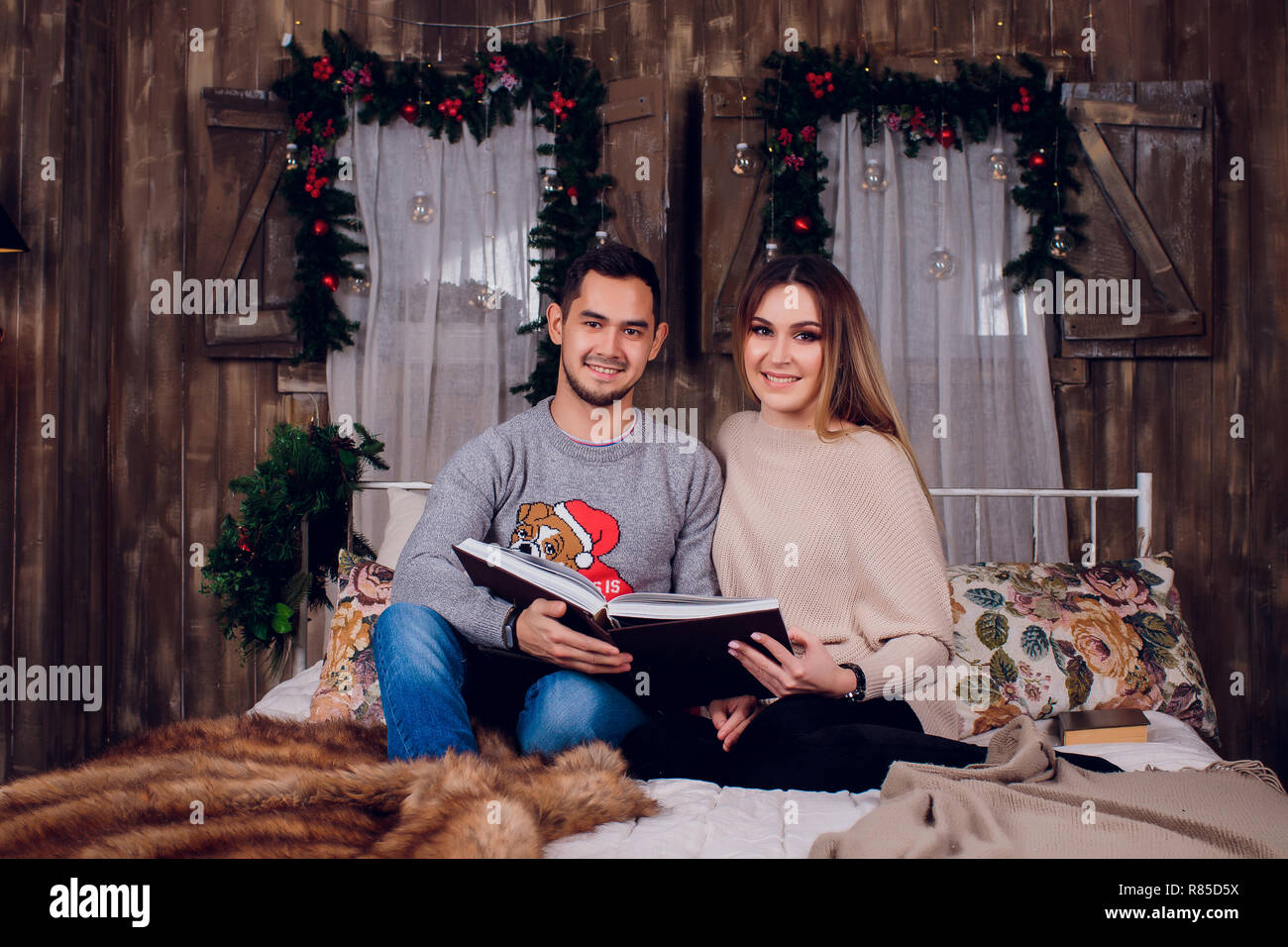 Die schöne Zeit zu Hause. Schöne junge Liebende Paar kleben aneinander und lächelnd, während Frau mit einem Buch. Stockfoto