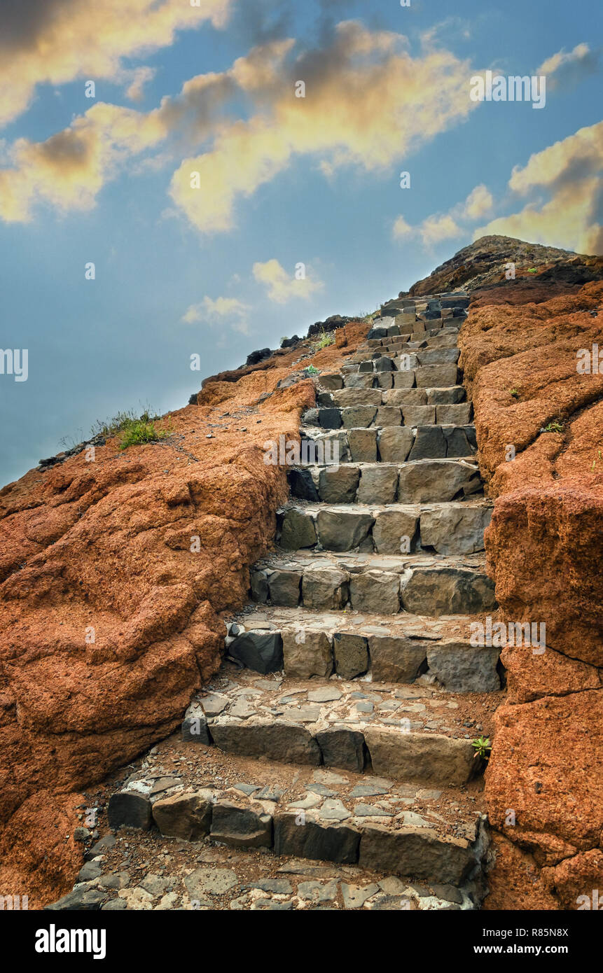 Vulkangestein mit natürlichen grauen Stein Treppe auf den Hügel verlassen. Blauer Himmel mit goldenen Sonnenuntergang Wolken. Landschaft mit Teil der populären hikin Stockfoto
