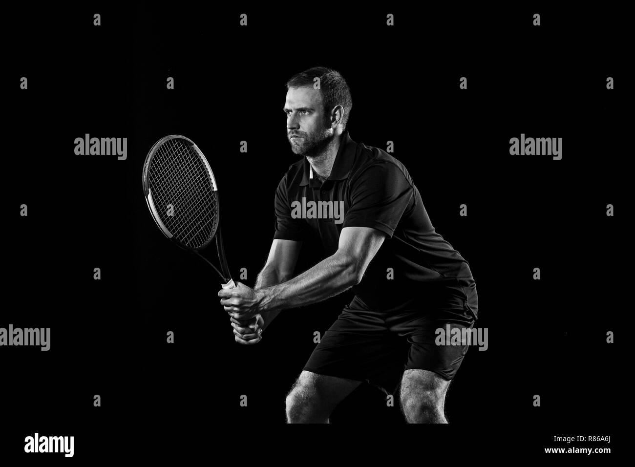 Die kaukasischen Mann Tennis auf schwarzen Hintergrund isoliert. Studio monochrome Schuss passen junge Spieler im Studio in Bewegung oder die Bewegung beim Sport Spiel. Stockfoto