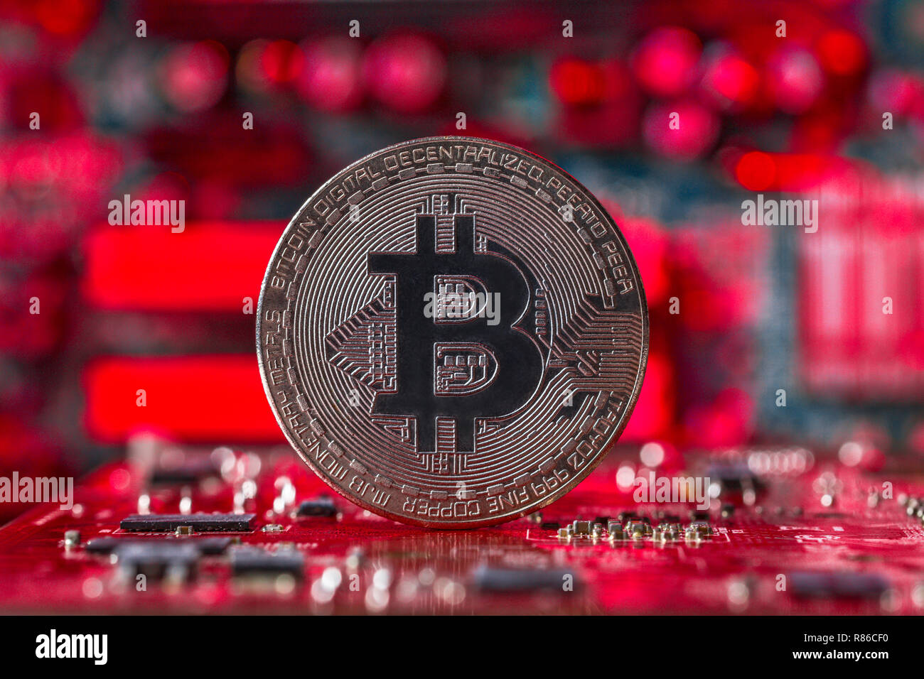 Silber Bitcoin auf Intergrated Circuit und roten verschwommenen Hintergrund Die plumeting Marktpreis Stockfoto