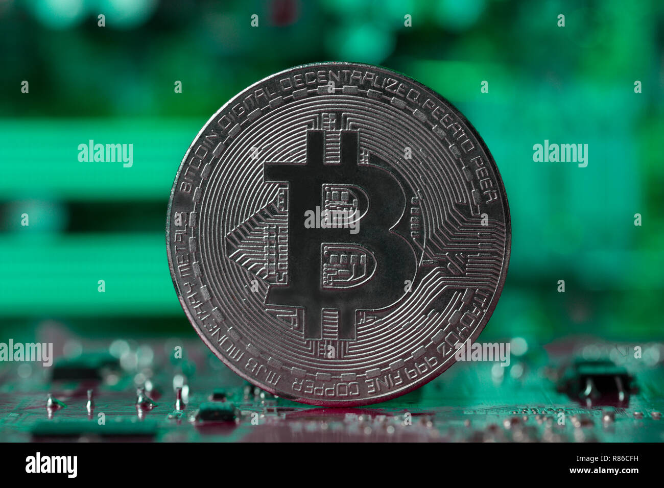 Silber Bitcoin auf Intergrated Circuit und Grünen verschwommenen Hintergrund Stockfoto
