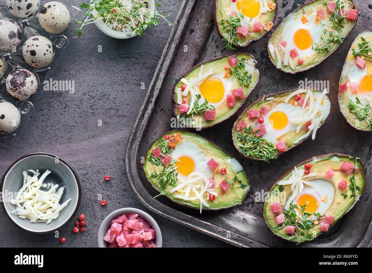 Keto Diät Teller: Avocado Boote mit Schinken würfeln, Wachteleier, Käse und Kresse Keimsprossen auf Metall Backblech Stockfoto