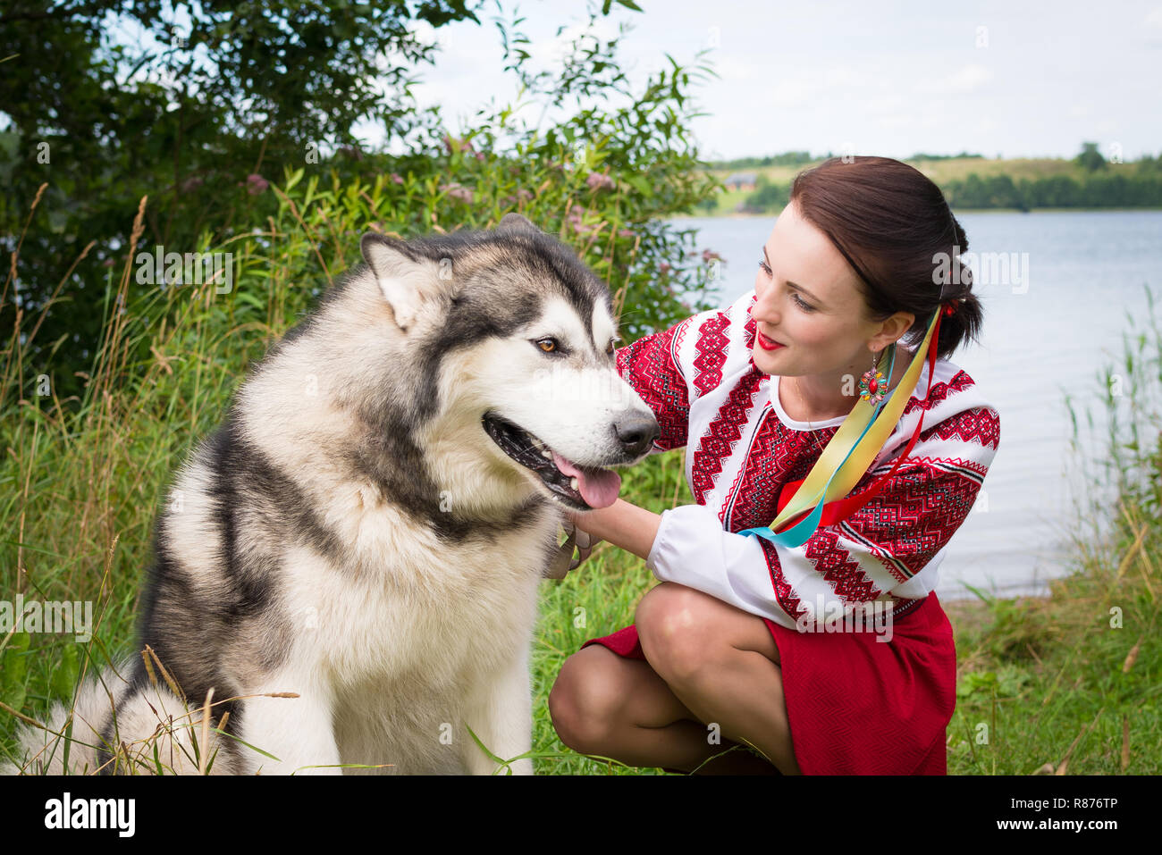 Mädchen Kleider in einem traditionellen slawischen Kleidung petting einen Hund Stockfoto