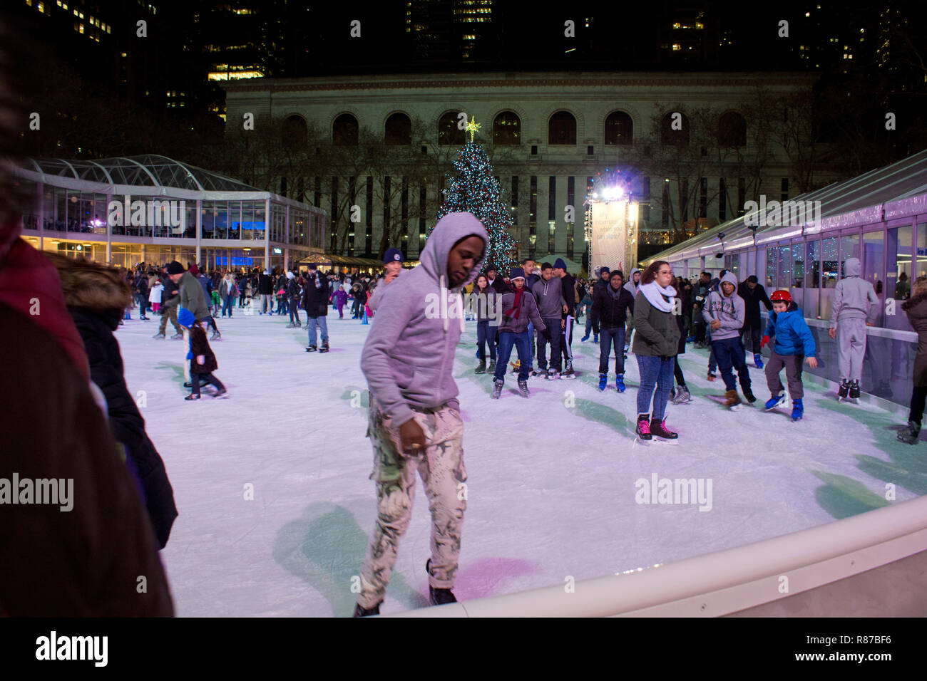 Citi Teich Eislaufbahn am Bryant Park in Manhattan mit Weihnachtsbaum auf dem Display. Leute Eislaufen in der Eissporthalle am Bryant Park in New York City. Stockfoto