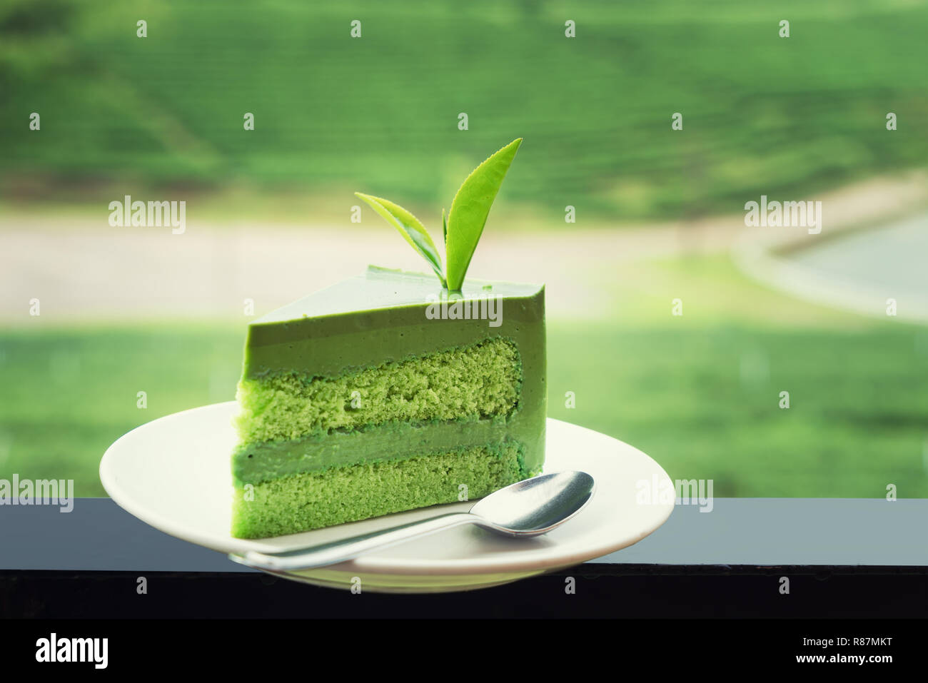 Nahaufnahme von frischen grünen Tee Kuchen auf weiße Platte mit Tee Plantage im Hintergrund. Stockfoto