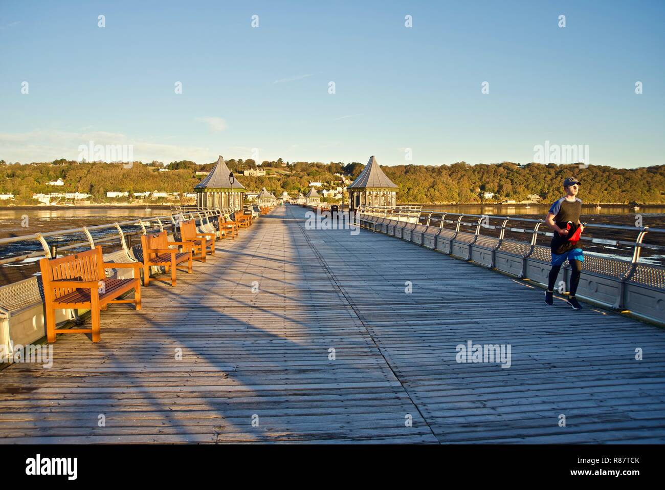 Ein junger männlicher Jogger läuft entlang Bangor Pier in der Morgendämmerung, Bangor, Gwynedd, Wales, Großbritannien Stockfoto