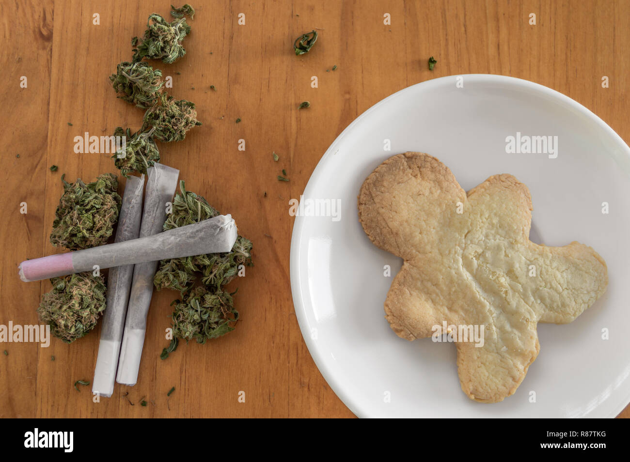 Stapel von Marihuana Knospen mit gewalzten Gelenke und eine Schale mit einem großen Cookie von Marihuana mit der Form eines Menschen. Frühstück oder ein Snack von Unkraut und Cookies. Stockfoto